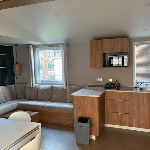 Intérieur d'un appartement moderne avec un salon, cuisine et coin repas en bois clair.